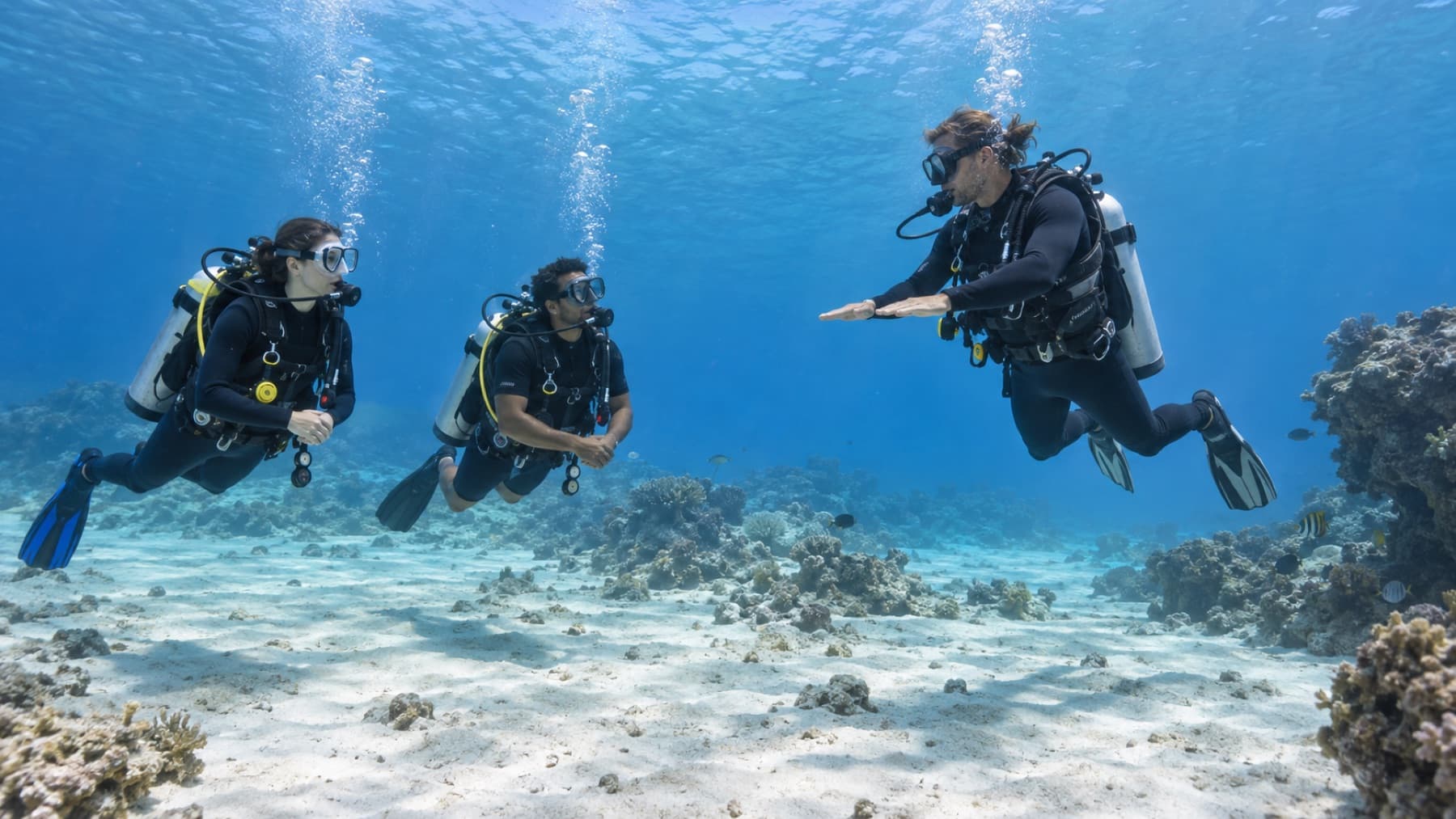 Instructor demonstrating buoyancy to two open-water scuba students